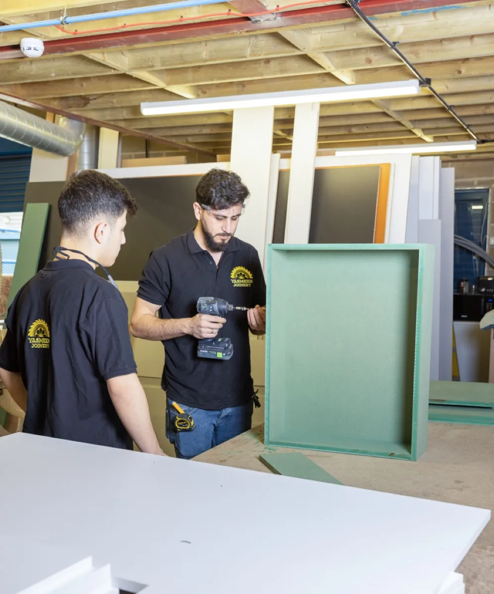 Two Yasmeen Joinery craftsmen reviewing a bespoke piece in the workshop