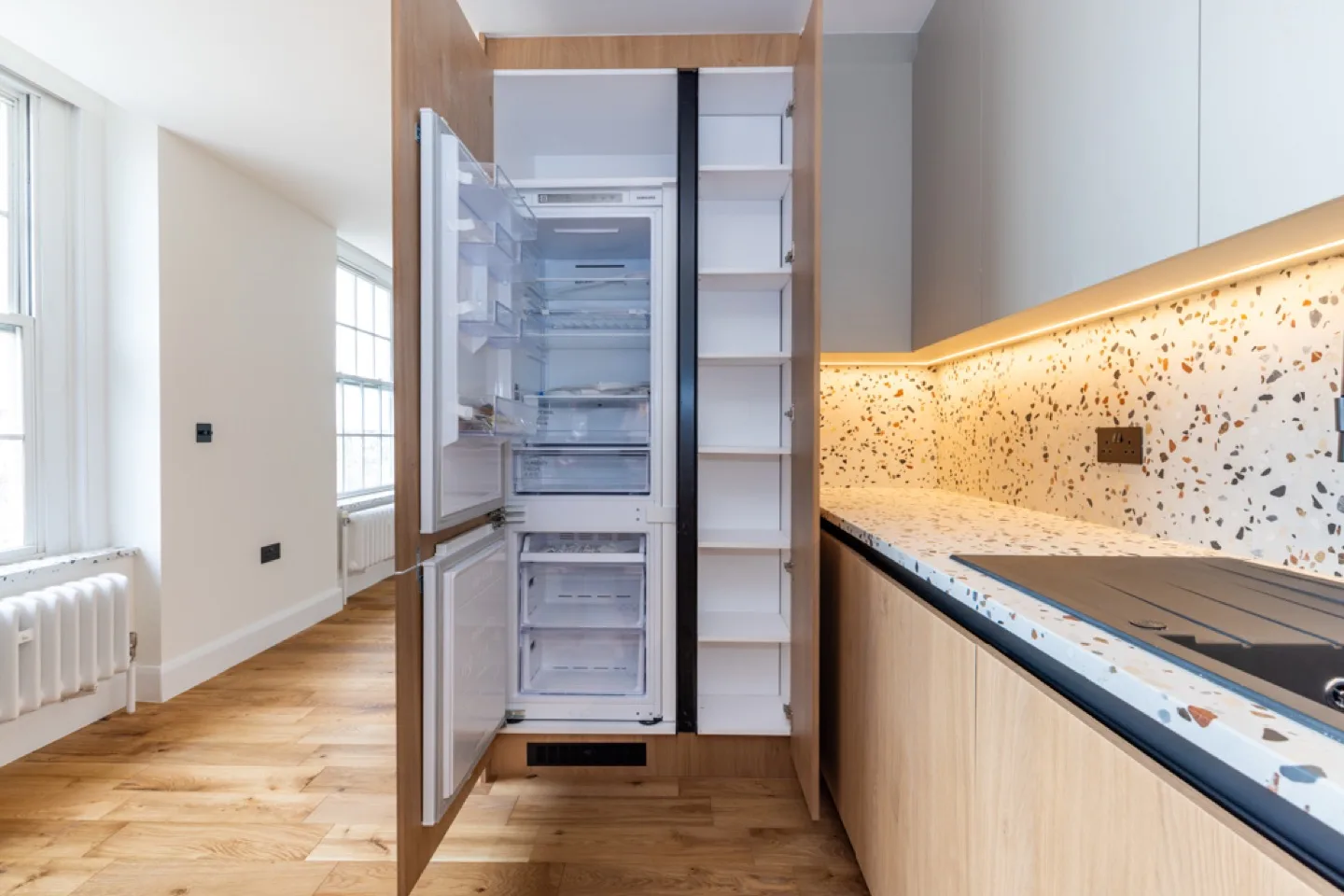 Integrated fridge-freezer and tall pull-out larder built into the oak kitchen unit