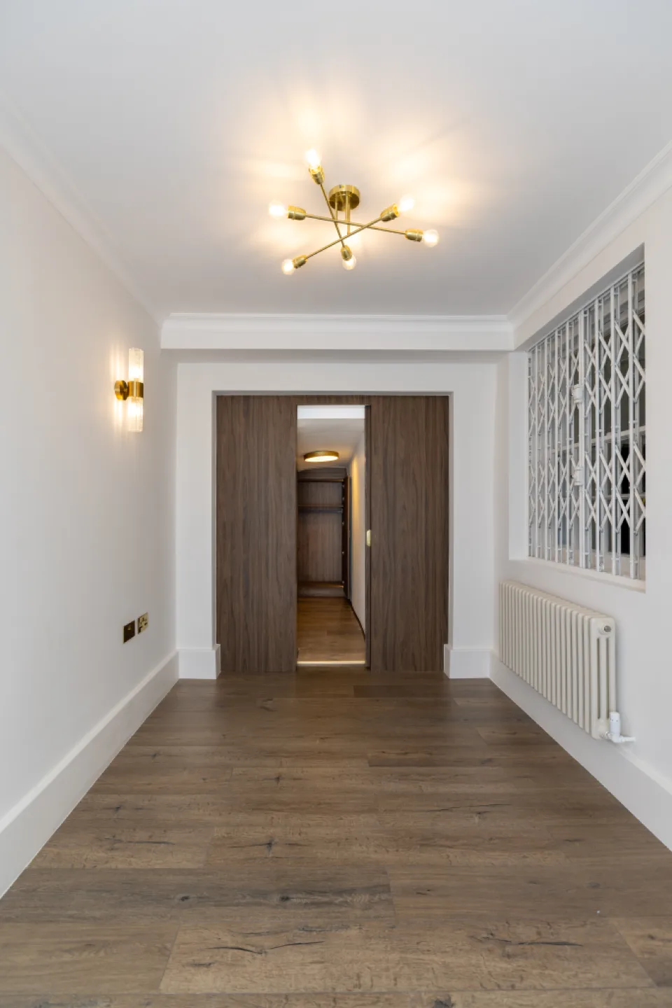 Walnut sliding pocket doors opened to reveal the walk-in wardrobe beyond, with oak flooring throughout