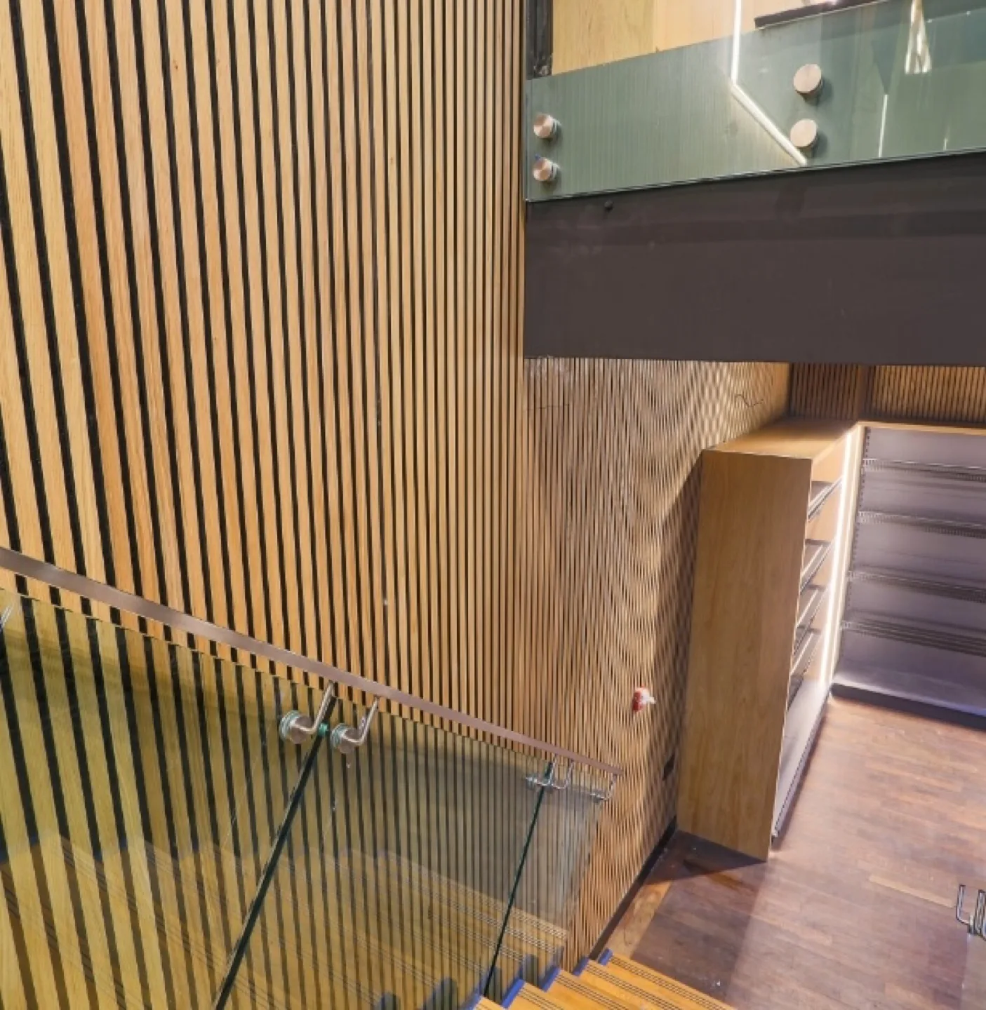 Slatted oak wall cladding above a stairwell with glass balustrade