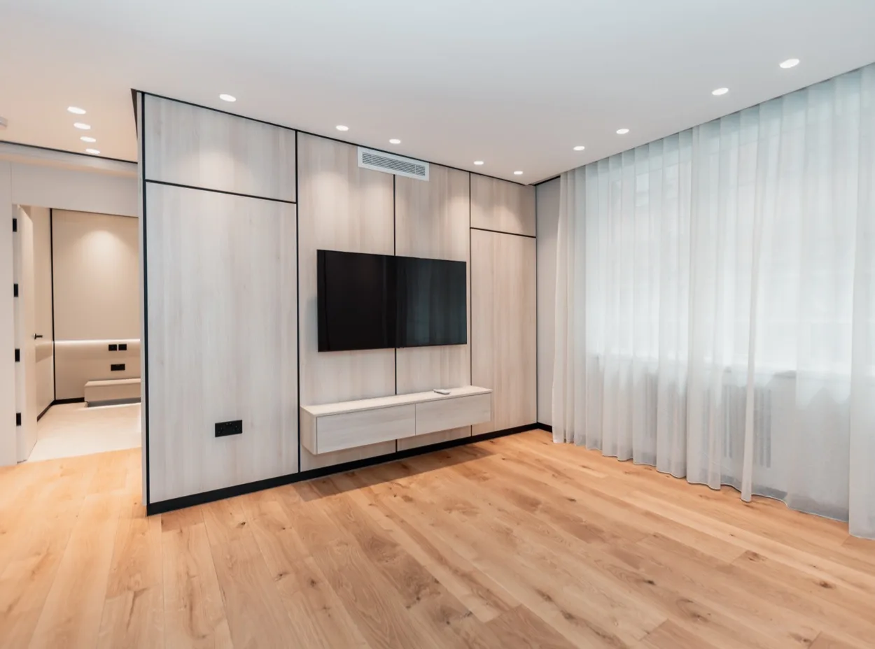 Bespoke pale-oak built-in media wall with a wall-mounted TV and no visible cables, by Yasmeen Joinery