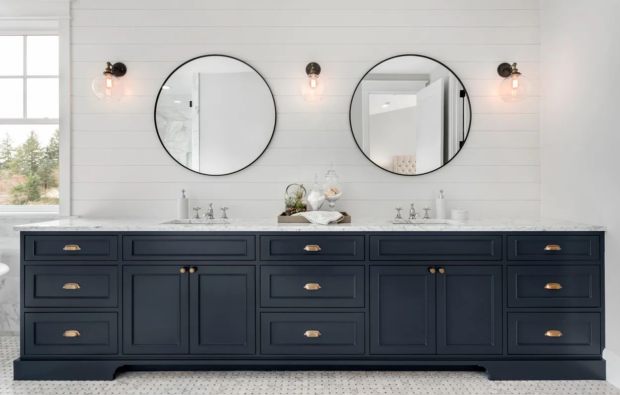 Bathroom vanity with twin round mirrors and dark blue cabinetry