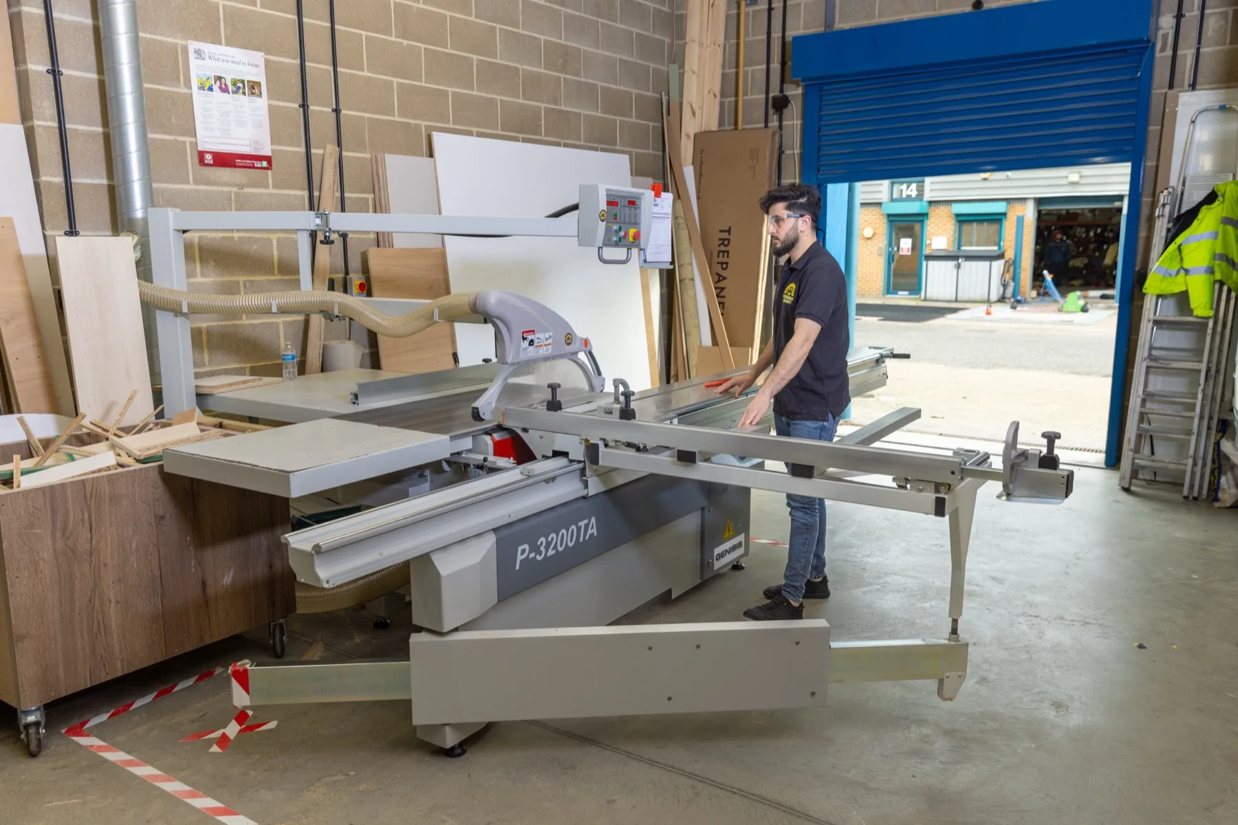 A Yasmeen Joinery craftsman cutting board on the panel saw in the Park Royal workshop, roller door open to the street