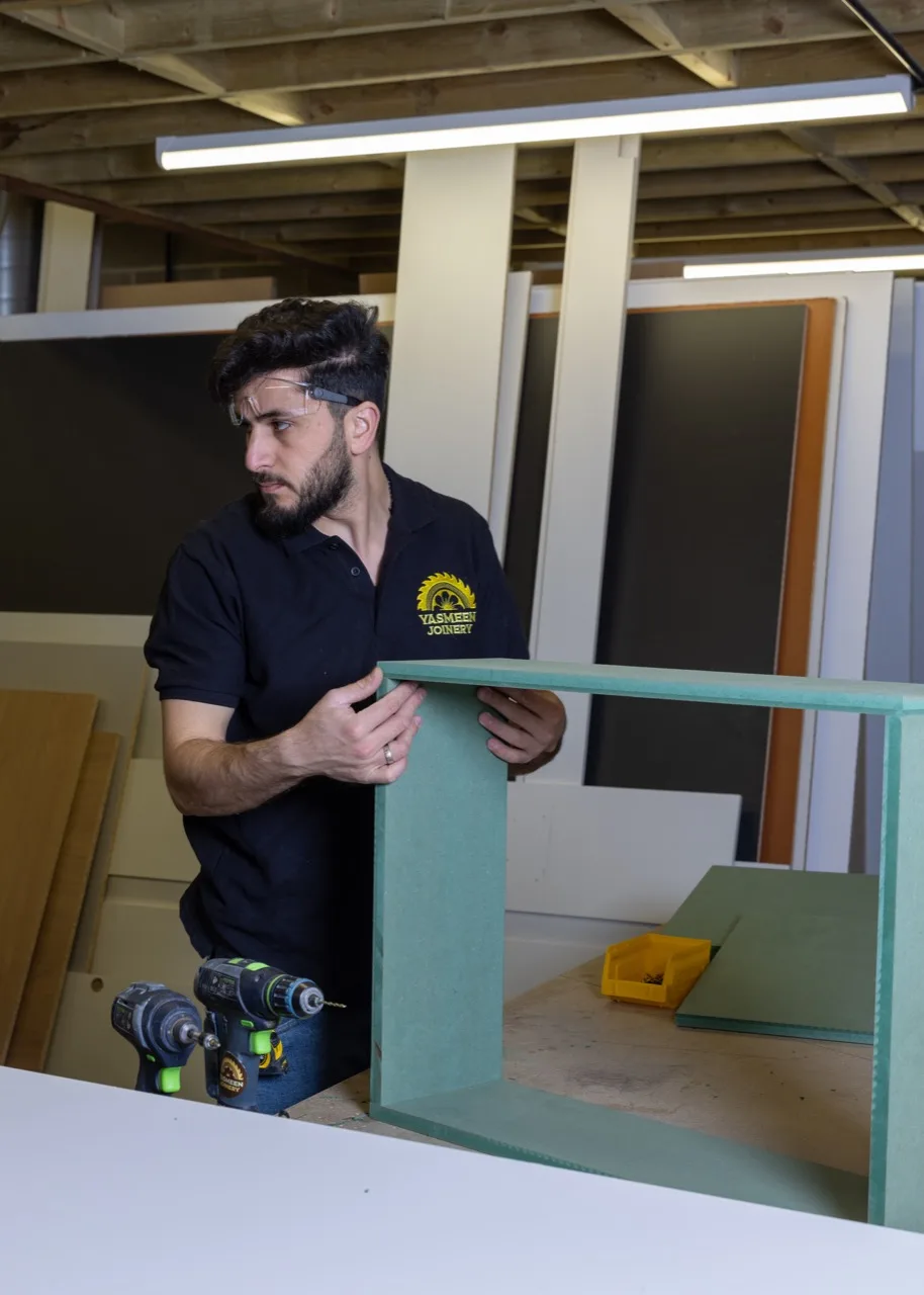 A Yasmeen Joinery craftsman assembling a cabinet carcass with a Festool drill