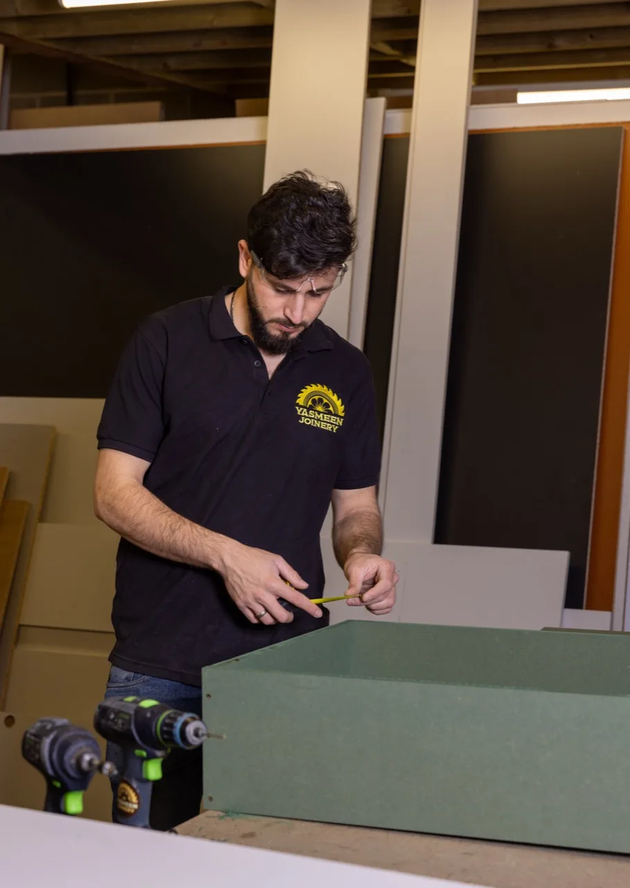 A Yasmeen Joinery craftsman measuring a carcass with a tape measure during the quality check